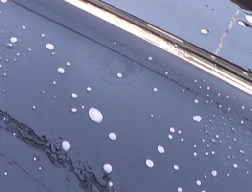 スプレー式の鉄粉除去クリーナーで鉄粉が反応している黒塗装の車