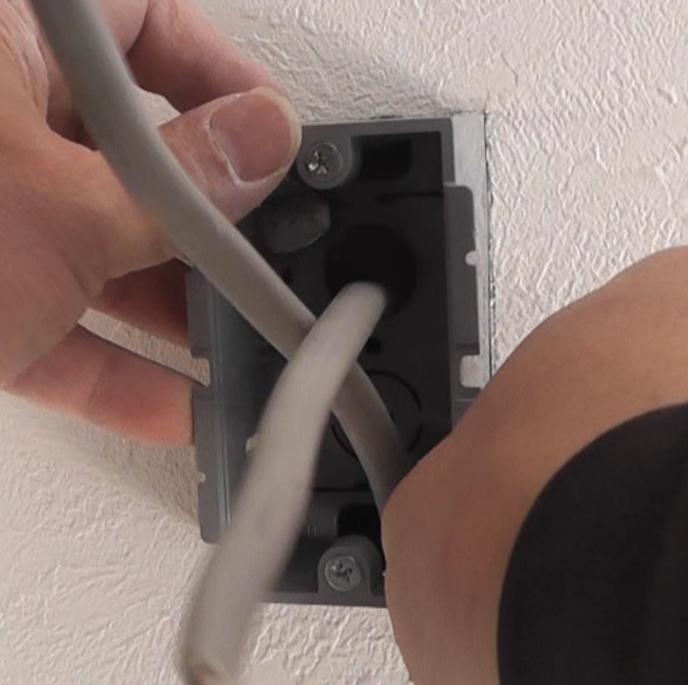 スイッチ用に開けた壁の穴から電源ケーブルを引き出してコンセントボックスを壁内に格納する