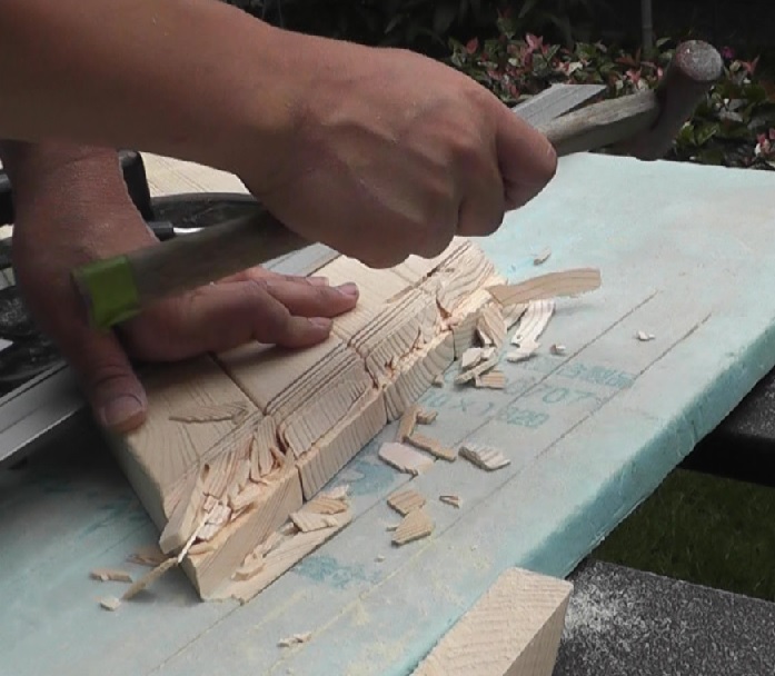 ガーデンテーブルの脚の一部を薄くするために丸ノコの刃を繰り返し入れた部分に残った木片はカナヅチで粉砕
