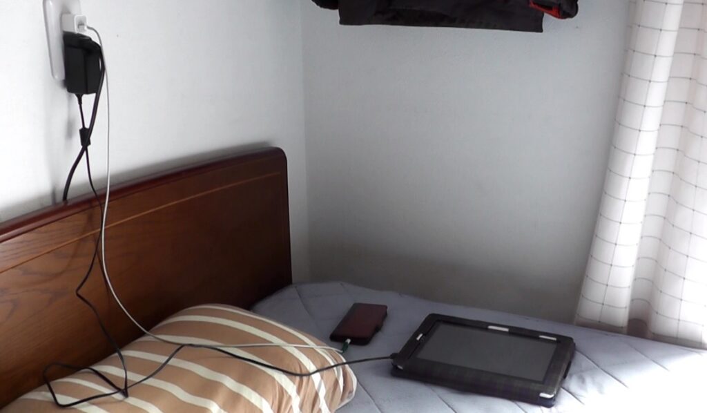 ベッドの上はスマホやタブレットなどの充電ケーブルが引き回されて乱雑になっている
