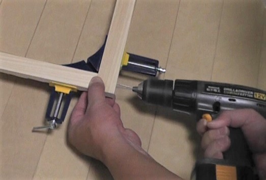コーナークランプを使用して垂直に固定した木材にネジ止め用の下穴を開ける