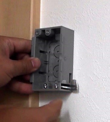間柱へネジ固定せず石膏ボードを挟み込んで固定するタイプのコンセントボックと同形状の穴を壁に開けていく